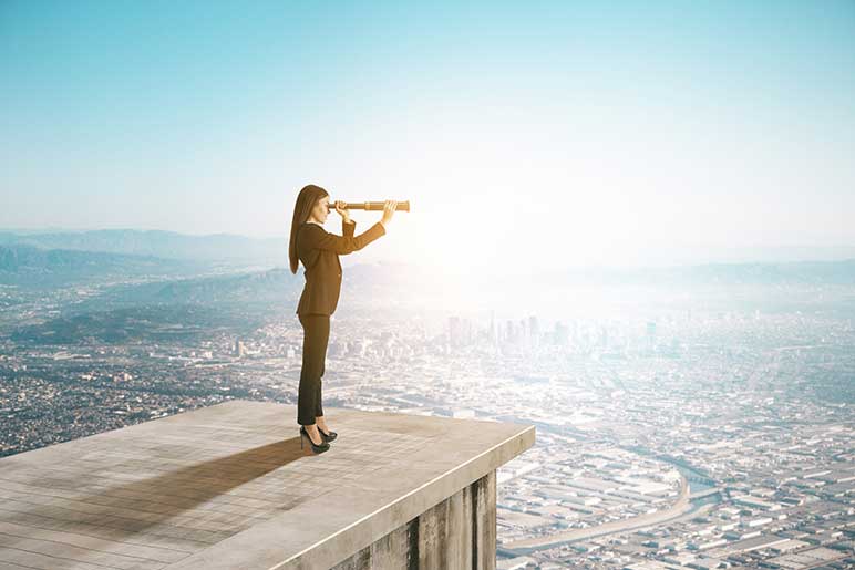 Businesswoman standing on the roof of a tall office building looking through a telescope at the cityscape below.